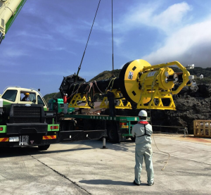 A crane lifts the PowerBuoy off a truck on land